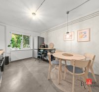 A kitchen in a 2-room apartment with a window, a dining table, and a floor with a wooden decor.