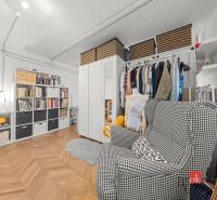 Interior with shelves, clothing, and a chair in a 2-room apartment; floor with wood decor.