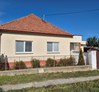 A family house in Ludanice with a white facade and a brick roof, surrounded by a fence.