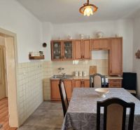 Kitchen in a family house with wooden decor, dining table, and rustic cabinets.