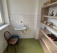 Bathroom in a family house with a sink, chair, and shelving system.