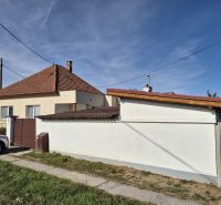 A family house in Ludanice with a sloped roof and fencing, with a parked car next to it.