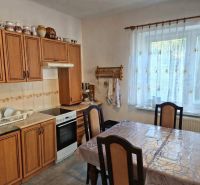A kitchen in a family house with wooden decor, a kitchen unit, a dining table, and decorations.
