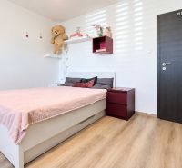 A bedroom in a family house with a pink bed and a wooden decor floor.