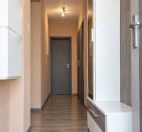 A hallway in a family house with a wooden decor floor and light-colored walls.