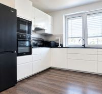 A kitchen unit with black appliances and a wooden decor floor in a family house.