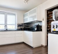 A kitchen in a family house with white cabinets and a wood-patterned floor.
