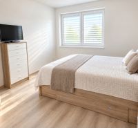 Bright bedroom with a bed, cabinet, and wood-decor flooring in a family house.