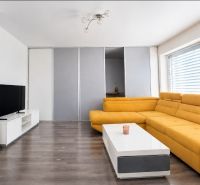 Living room in a family house with a yellow sofa, TV, and a wooden decor floor.