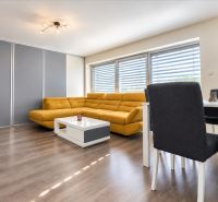 A living room with wood-patterned flooring, a yellow sofa, and a dining table.