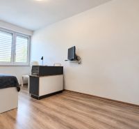 A bedroom in a family house with a bed, a table, and a wooden decor floor.