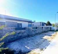 A family house in Horné Saliby with a concrete fence on a sunny street.