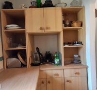 A kitchen cabinet in a family house with shallow shelves and a white refrigerator.