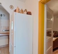 A kitchen in a family house with a refrigerator, brick decor, and wooden furniture.