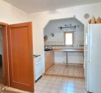 A kitchen in a family house with a ceramic floor, a gas stove, and a white refrigerator.