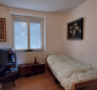 A room in a family house with a bed, a television, and a wooden decor floor.