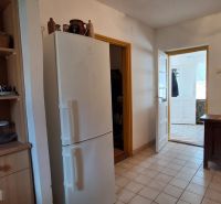 A kitchen in a family house with a white refrigerator and wooden furniture.