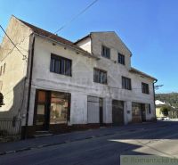 The exterior of a building in Modrý Kameň with commercial spaces, next to the road and nature.