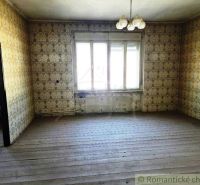A room with wallpaper and a wooden decor floor, illuminated by a large window.