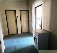 An interior with a washing machine, doors, and wallpapered walls in commercial premises.