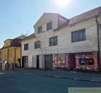 A building with commercial spaces in the town of Modrý Kameň, visible across the street.