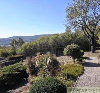 A cottage in Modrý Kameň with a landscaped garden and a view of the hilly countryside.