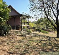 A cottage in Modrý Kameň, surrounded by greenery and trees in a beautiful rural setting.