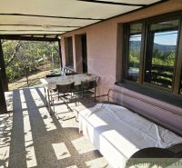 A covered terrace at the cottage in Modrý Kameň with seating and a view of nature.