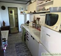 A kitchenette in a cottage with white cabinets and appliances, next to a bathroom.