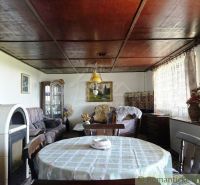 The interior of a cabin with a wooden decor floor, wooden ceiling, table, and fireplace.