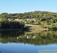 A view of a pond with trees and hills in the Gardens in Krupina.