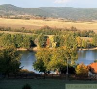A lake surrounded by autumn trees and hills in the gardens in Krupina.