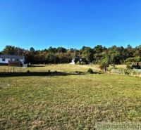 Extensive gardens with buildings in Krupina, surrounded by greenery and blue sky.