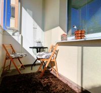 A balcony with two folding chairs and a carpet in a 2-room apartment.