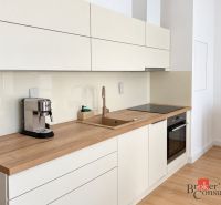 Kitchen in a studio apartment with wood decor flooring, cream cabinets, coffee maker.