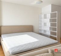 Bedroom in a studio apartment with a bed and white shelves, floor with wood decor.