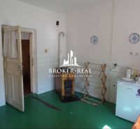 A room in a family house, simple furnishings, stove, green floor, light wall.