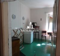 A room in a family house with furniture, a green floor, and white walls.