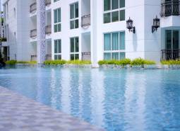 Apartment construction in Pattaya with landscape architecture and a pool in the background of the buildings.