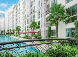 Construction of apartments in Pattaya with a swimming pool, palm trees, and an apartment complex for sale.