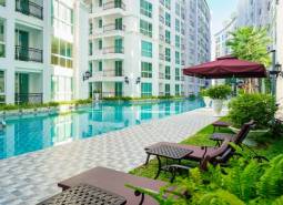 Pattaya, construction of apartments with a swimming pool, deck chairs, and umbrellas in a residential area.