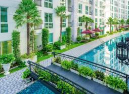 Apartment construction in Pattaya with a swimming pool, greenery, balconies, and outdoor relaxation areas.