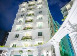 A building under construction of apartments in Pattaya with a white facade and balconies with plants.