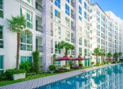 Apartment construction in Pattaya: White apartment complex with palm trees and a swimming pool.