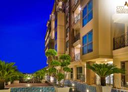 Nighttime construction of apartments in Pattaya with illuminated balconies and green surrounding landscaping.