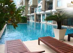 A swimming pool during the construction of apartments in Pattaya, surrounded by greenery and loungers.
