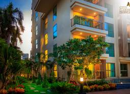 Construction of apartments in Pattaya with a tropical garden and bright balconies in the evening light.