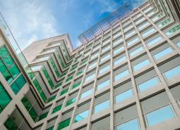 Apartment construction in Pattaya: a modern building with glass windows under an azure sky.