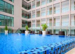 A swimming pool under construction in a residential complex in Pattaya, surrounded by glass buildings and lounge chairs.