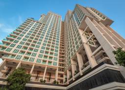 The construction of apartments in Pattaya shows high residential buildings with trees against the backdrop of a blue sky.